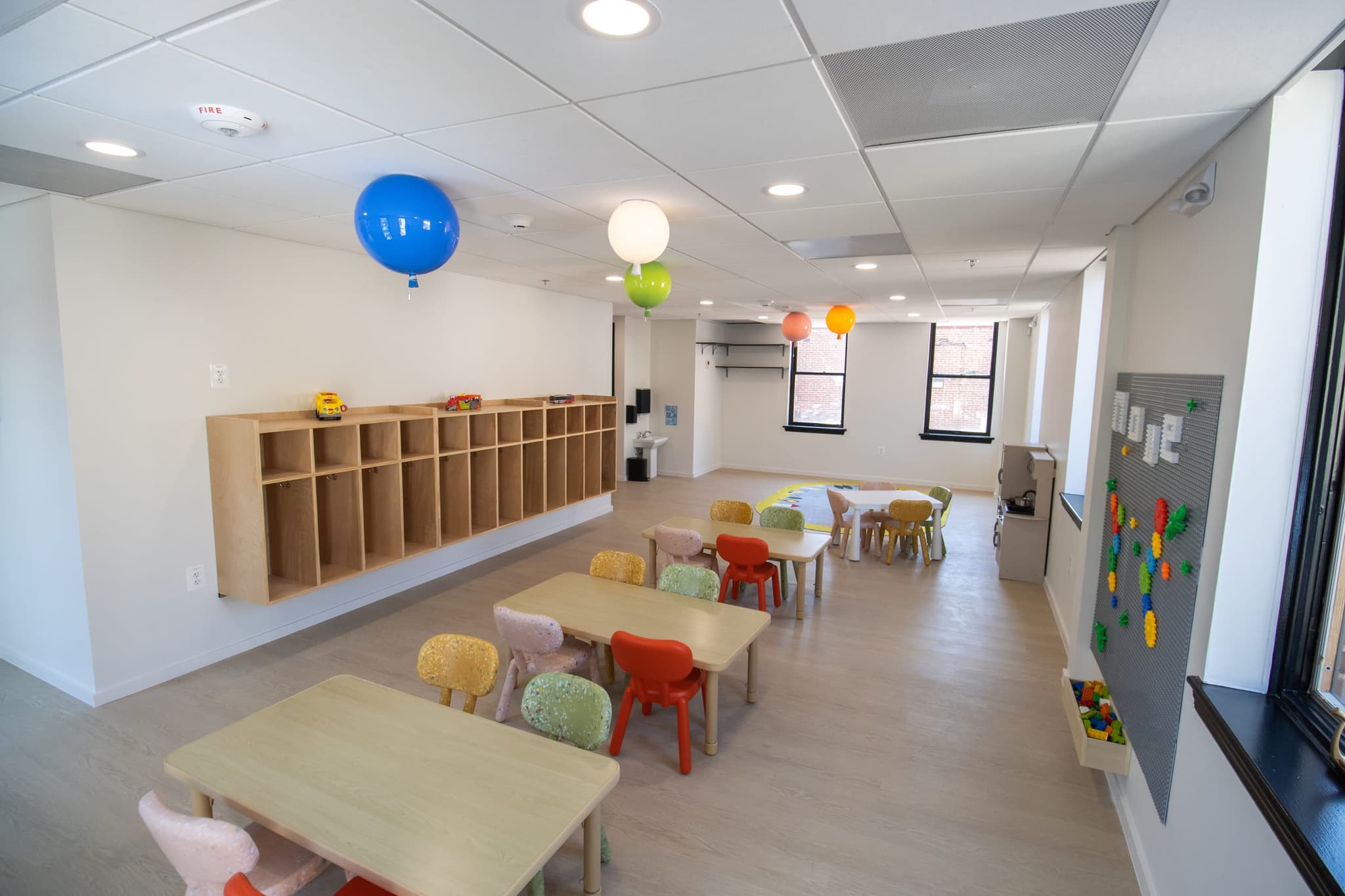 classroom with hanging balloons, cubbies and activity tables